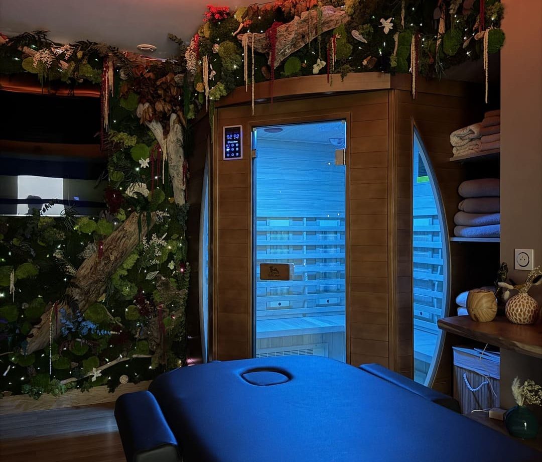 Espace bien-être intime chez Mia Casa à Saint-Mitre-Les-Remparts avec table de massage, sauna en bois et mur végétal éclairé.